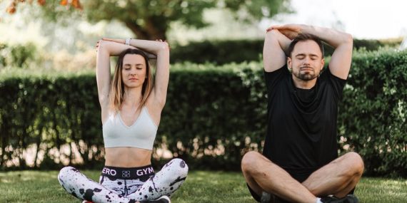 A couple practicing yoga and meditation in a serene outdoor setting, enhancing well-being.