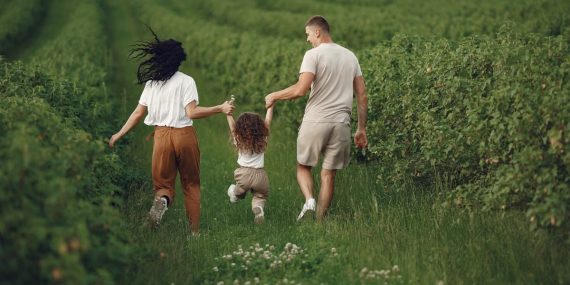 A joyful family strolls through a lush green field, enjoying quality time together.
