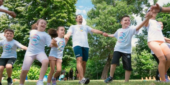 Group of joyful children playing outdoors with an instructor in a sunny park.